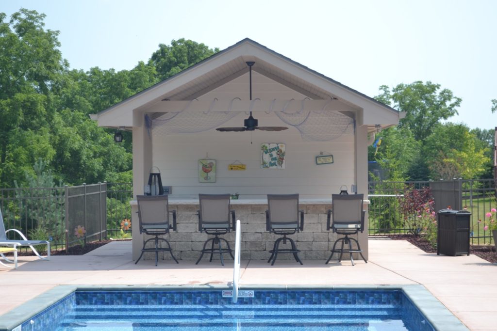 Custom pool house with bar seating and covered patio overlooking swimming pool in Wisconsin.