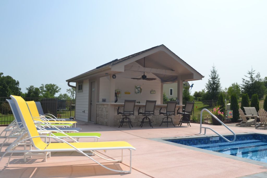 Custom pool house with bar seating and covered patio overlooking swimming pool in Wisconsin.